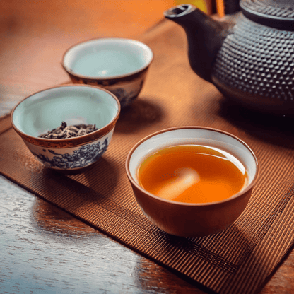 China Oolong tea in a cup with traditional teapot and bowls on a wooden table.